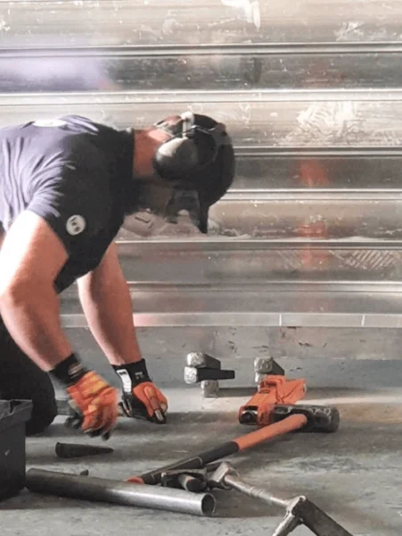 Man working on installing a garage door surrounded by tools